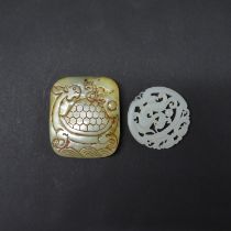 A Chinese carved mutton fat jade dragon amulet, dia. 5cm, together with a further jade amulet.