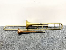 An Evette and Schaeffer brass trombone together with a post horn.