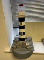 A working scratch built floating model of a lighthouse. Used as turning point for model boat racing,