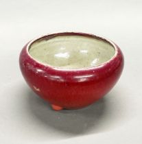 An 18th/early 19th C Chinese porcelain sang de boeuf bowl, with three feet, dia. 22cm.