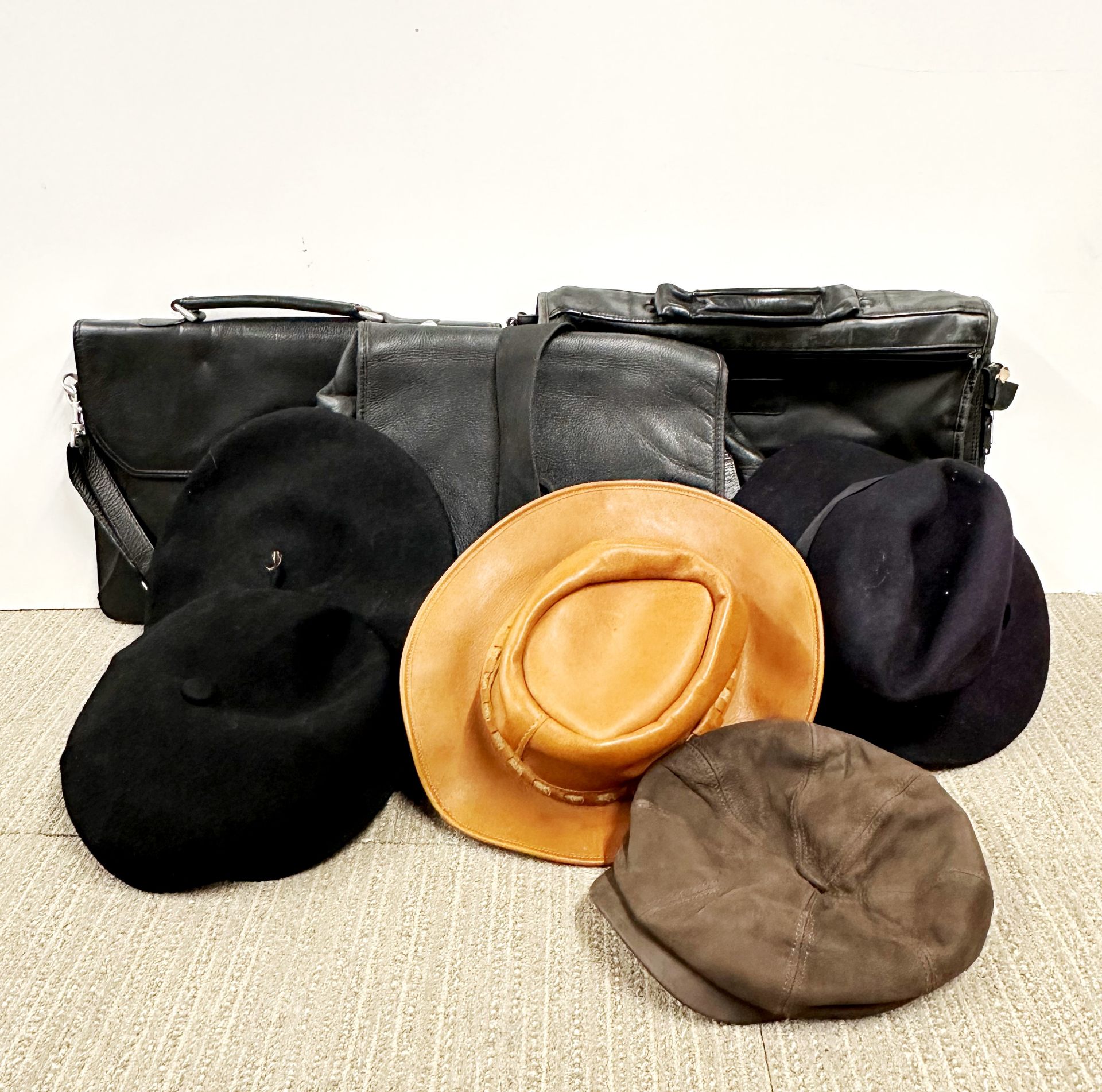 A group of vintage leather bags and hats.