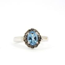 A 915 silver cluster ring set with an oval cut blue topaz surrounded by black diamonds, (N.5).