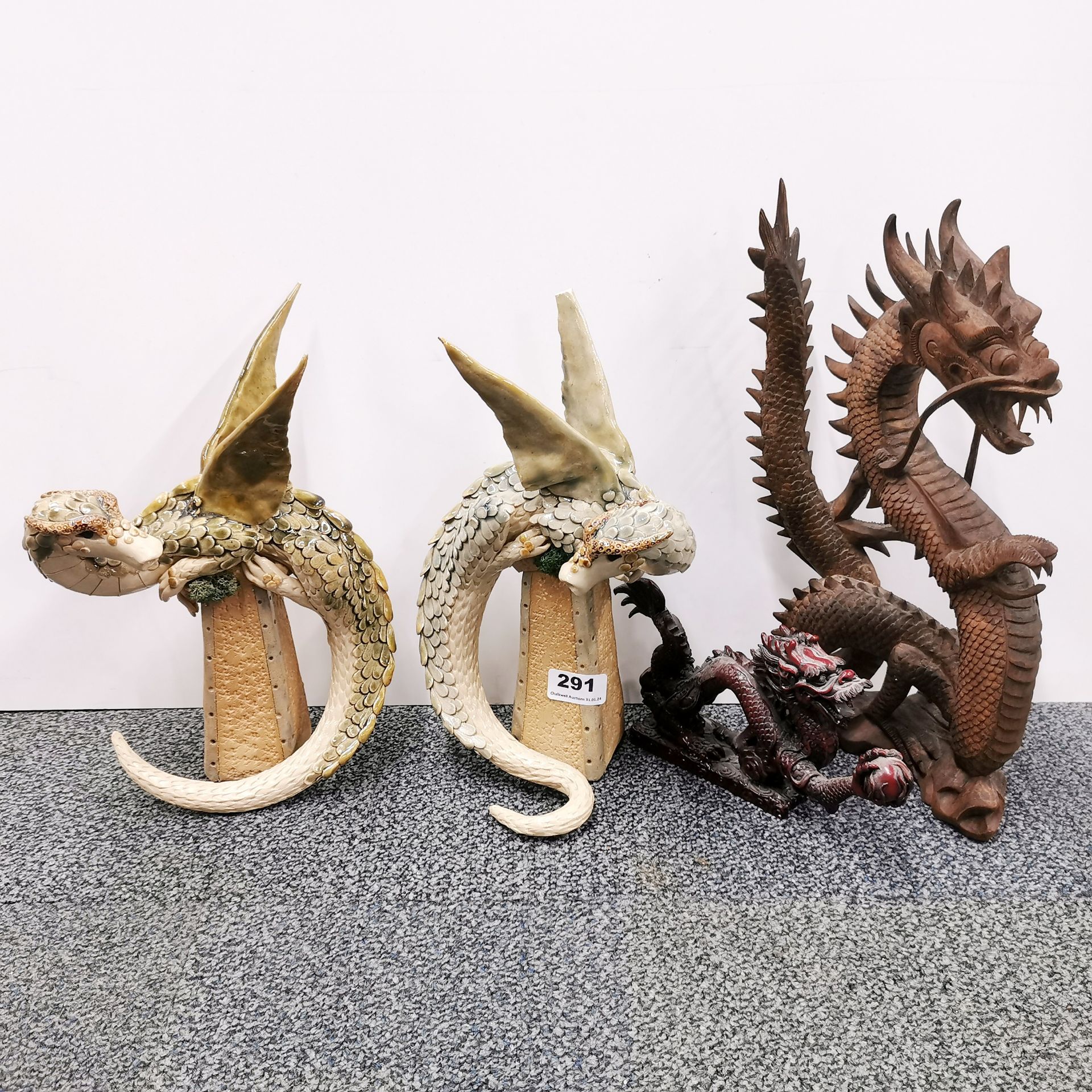 Two glazed pottery figures of dragons by Karen Lainson, H. 30cm, together with a carved wooden