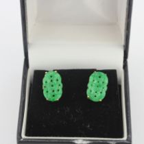A pair of yellow metal (tested minimum 9ct gold) carved jade stud earrings, L. 1.5cm.