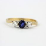 An 18ct yellow gold (stamped 18ct) ring set with a sapphire flanked by diamonds, (N.5).