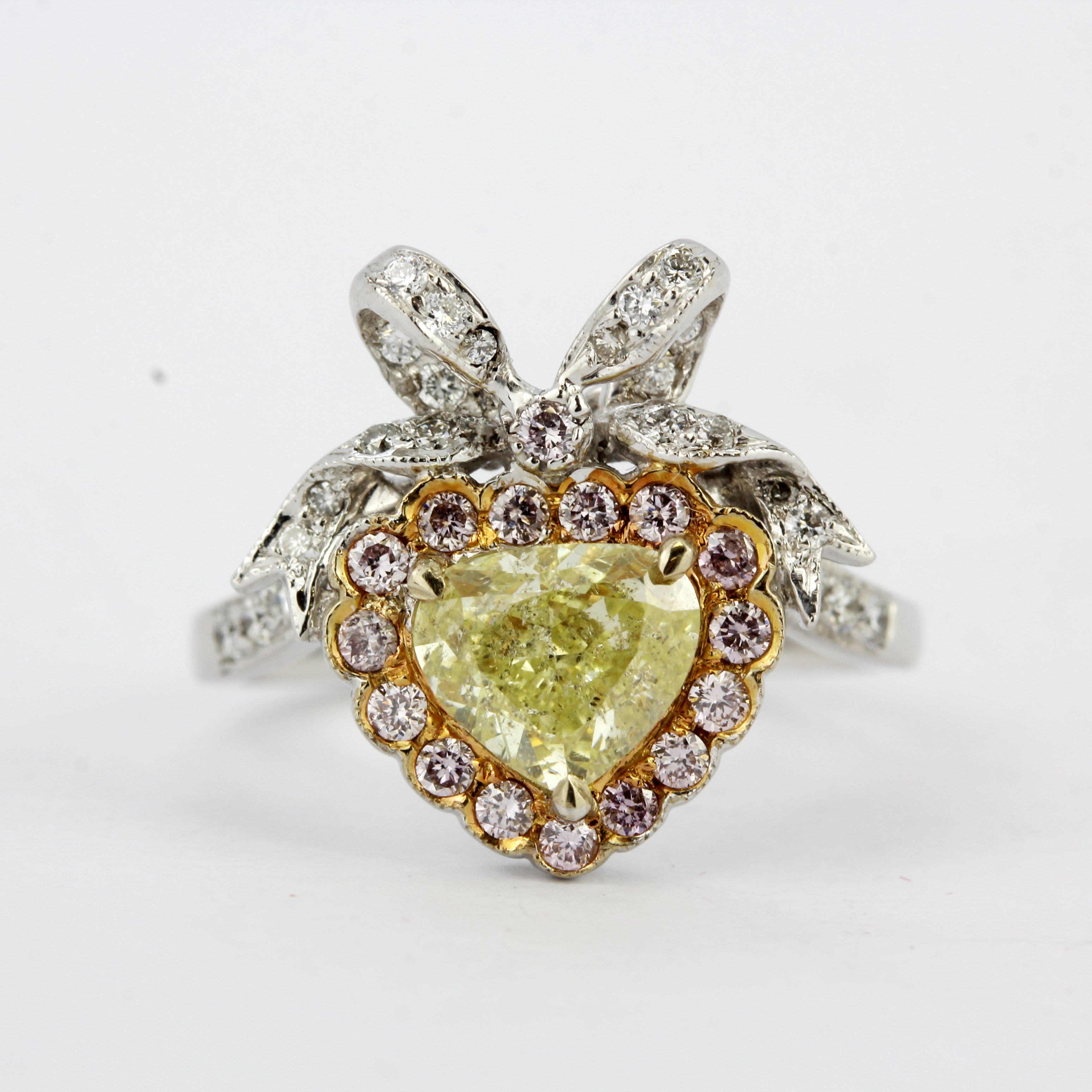 An 18ct white gold ring set with a heart brilliant cut fancy yellow diamond, surrounded by pink