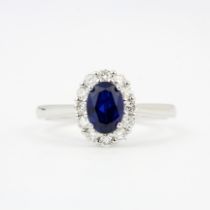 An 9ct gold cluster ring set with an oval cut sapphire surrounded by brilliant cut diamonds, (O).