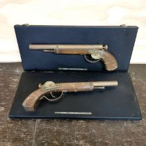 A pair of wall mounted replica pistols.