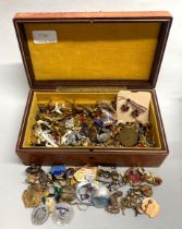 A box of mixed pins, brooches, badges and other costume jewellery.