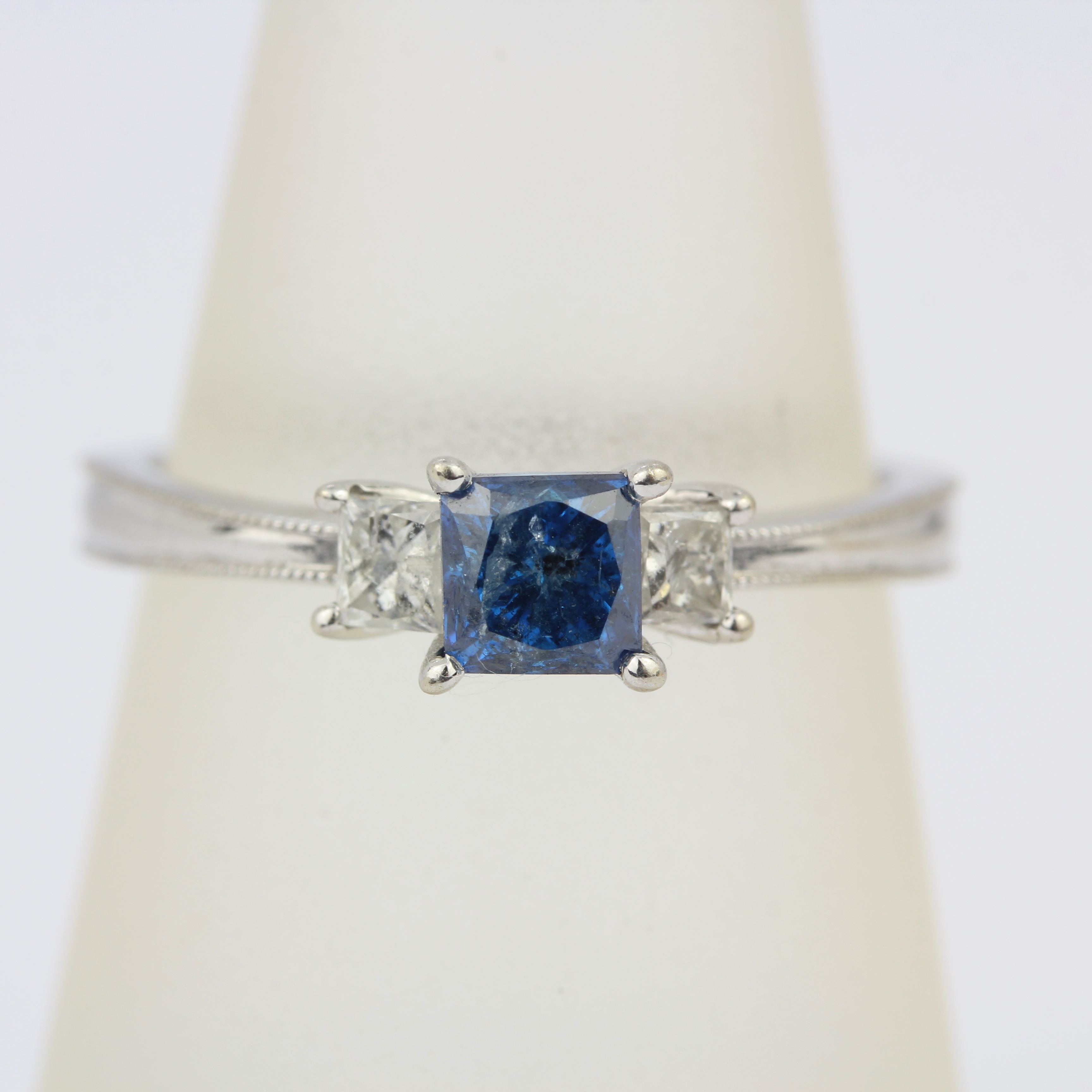 A 14ct white gold ring set with a princess cut fancy blue diamond and princess cut diamond set