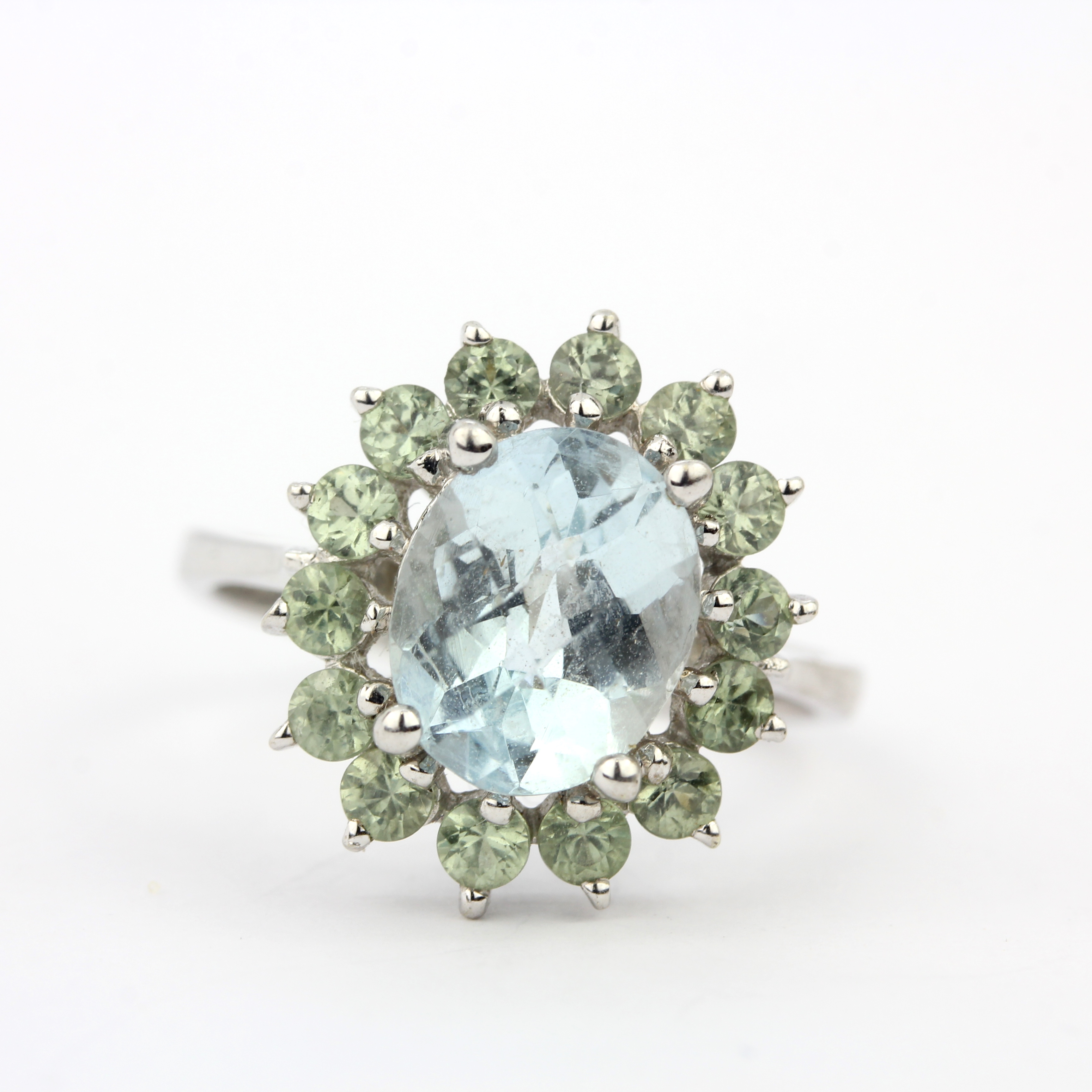 A 9ct white gold ring set with checker board cut aquamarine surrounded by green amethyst, (P).