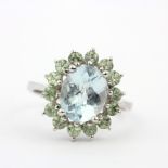 A 9ct white gold ring set with checker board cut aquamarine surrounded by green amethyst, (P).