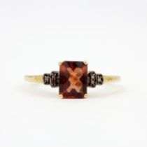 A 9ct yellow gold ring set with a checker board cut red topaz and fancy red diamond set