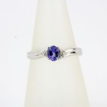 A hallmarked 9ct white gold ring set with an oval cut tanzanite and diamond set shoulders, (M.5).