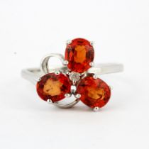 A hallmarked 9ct white ring set with oval cut hessonite garnets and a diamond, (N.5).