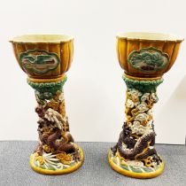 An impressive pair of large Chinese glazed terracotta planters on stands, relief decorated with