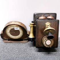 A wall mounted telephone and a vintage oak clock.