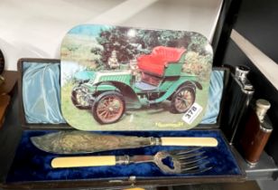 A set of vintage table mats with a cased fish serving set and two spirit flasks.