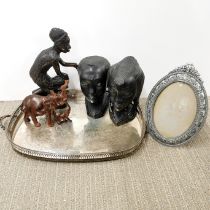 A silverplated tray with a group of African carved wooden figures and a picture frame.
