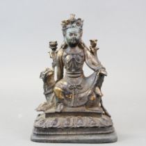 A Chinese bronze figure of a deity seated on a lion dog, H. 23cm.