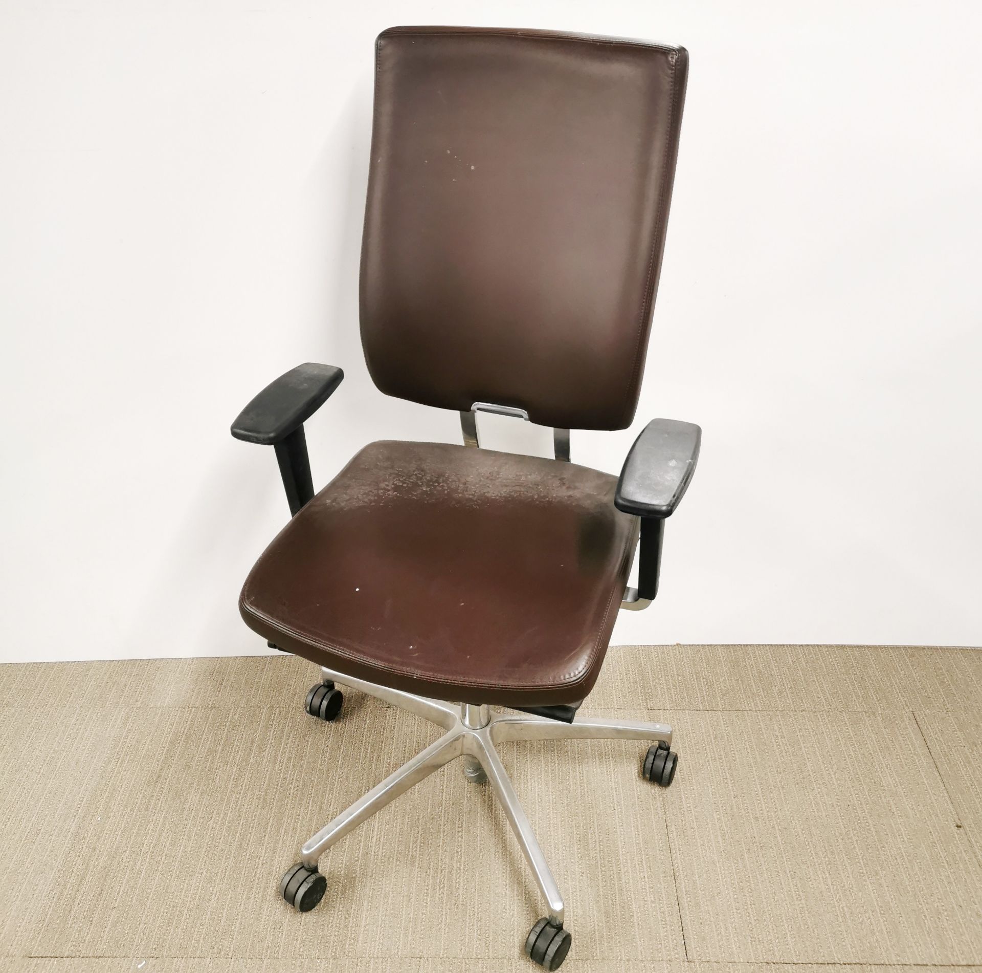 An adjustable faux leather and chrome revolving desk chair.