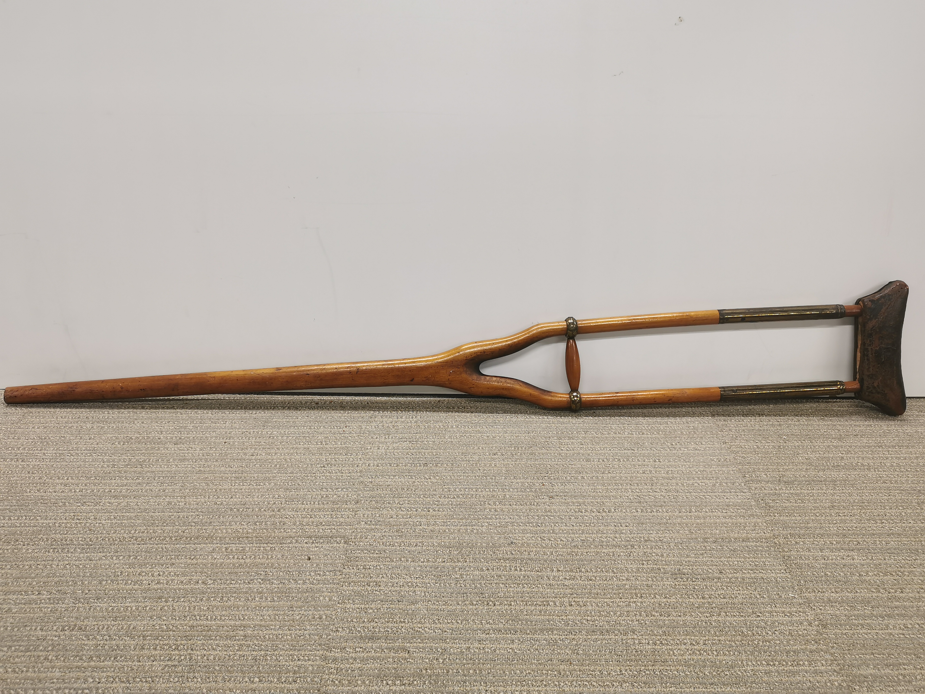 An early brass wood and leather crutch.
