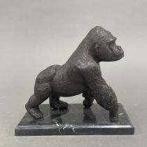 A cast bronze figure of a gorilla on a grey marble base. H. 18cm.