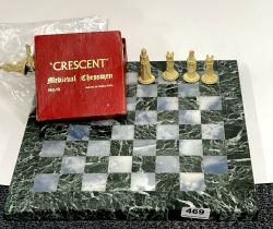 A polished marble chess board with a set of plastic medieval chess pieces, 35 x 35cm.