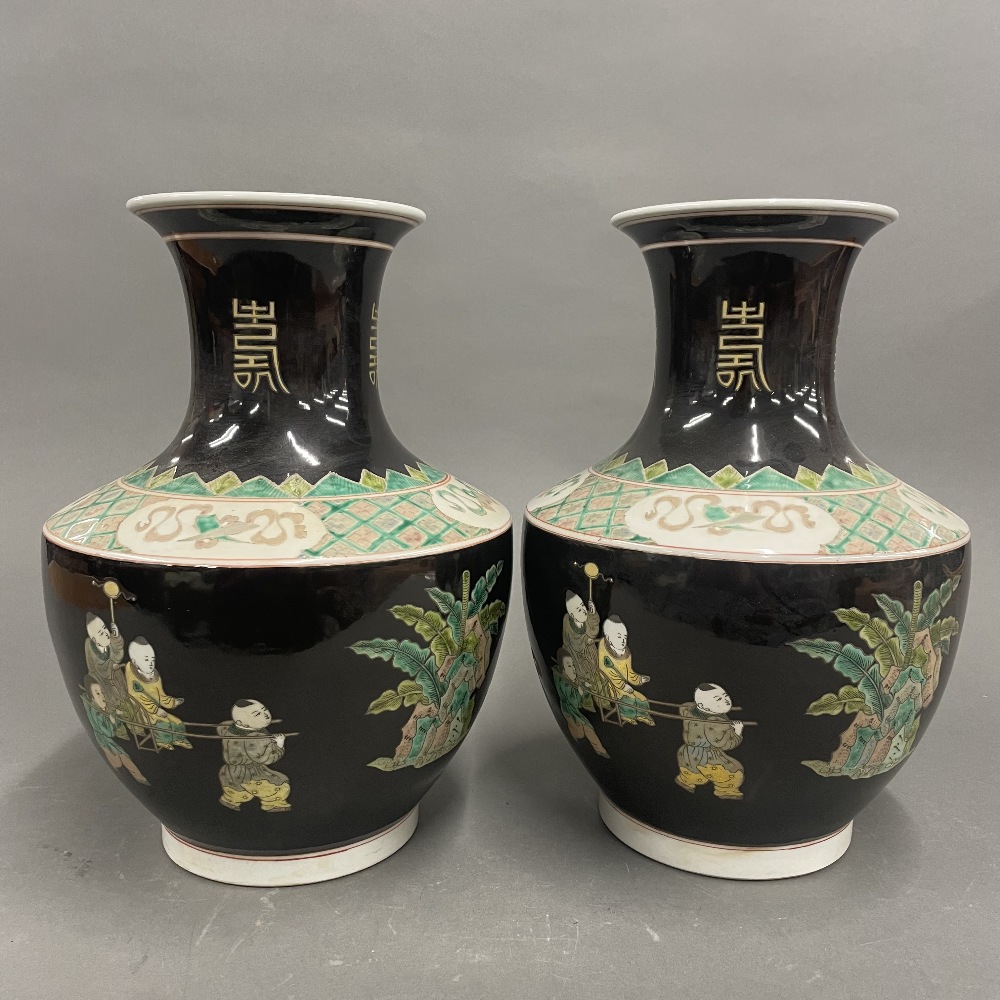 A pair of Chinese famille noire decorated porcelain vases featuring children playing games, H.