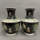 A pair of Chinese famille noire decorated porcelain vases featuring children playing games, H.