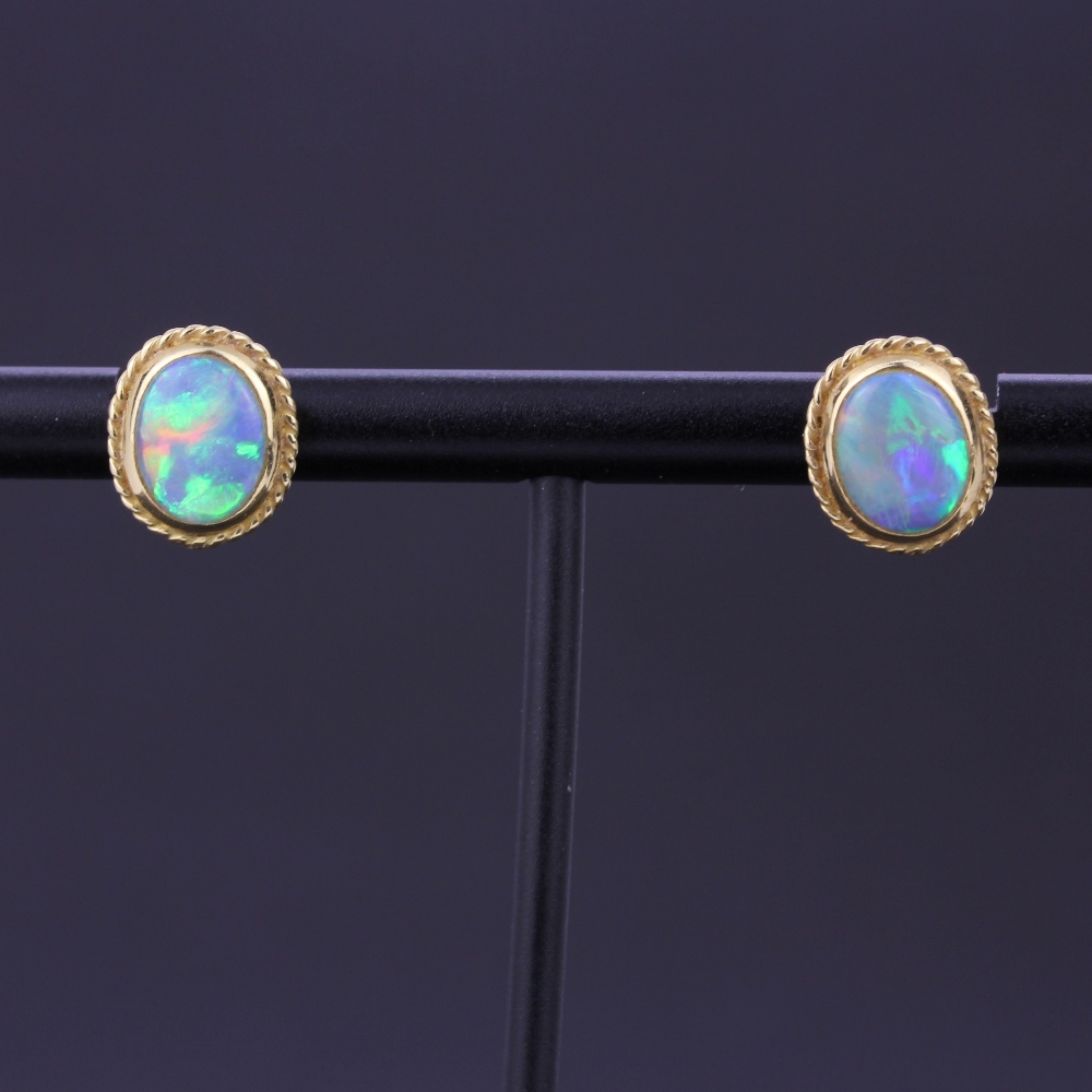 A pair of yellow metal opal set stud earrings, L. 1cm. With 18ct gold backs.