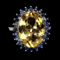 A 925 silver ring set with a large oval cut citrine surrounded by sapphires, (O.5).