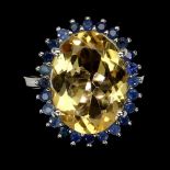 A 925 silver ring set with a large oval cut citrine surrounded by sapphires, (O.5).