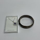 A vintage silver hinged bangle with a silver pendant and chain.