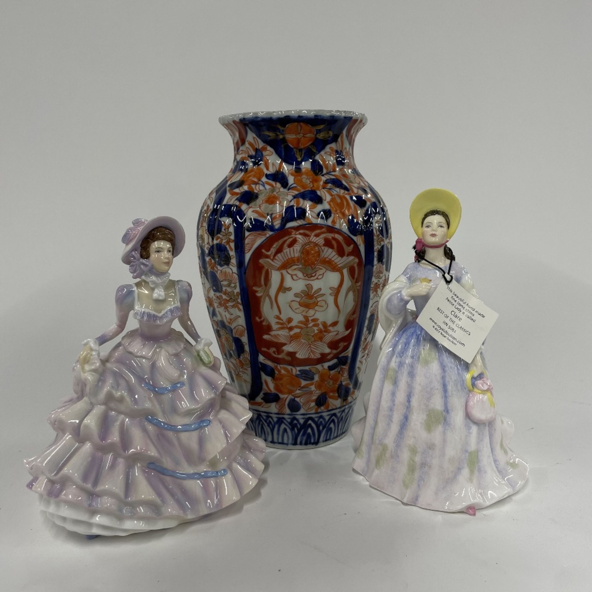 An Imari vase and two Royal Doulton lady figures.