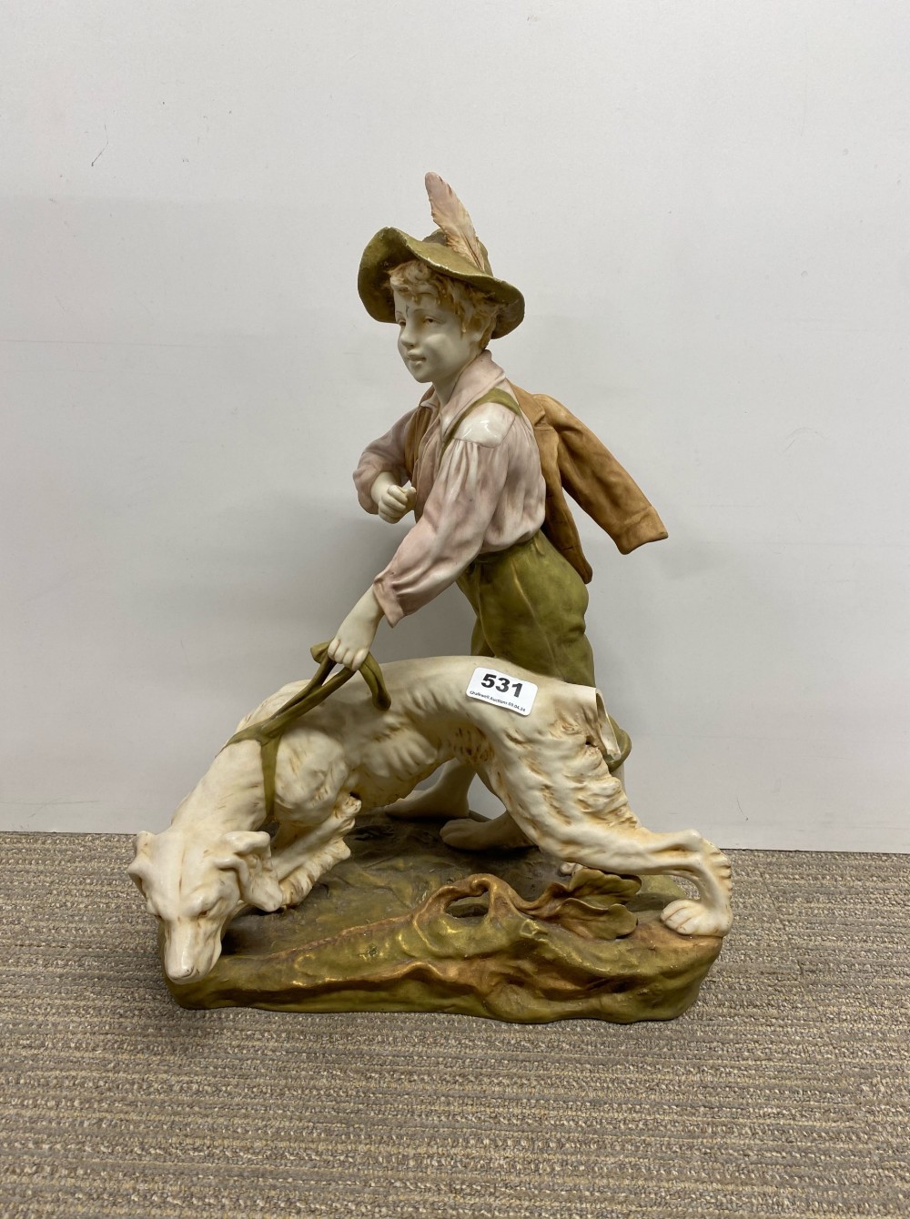 A large Royal Dux porcelain figure of a boy with a dog. Tail missing and small chip to hat.