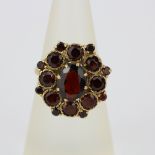 A hallmarked 9ct yellow gold garnet set cluster ring, (M).