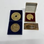 Two bronze medallions and a Chinese brass coin with one stand.