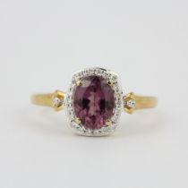 A 14ct yellow gold ring set with an oval cut tourmaline surrounded by diamonds, (O).