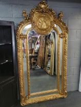 A very large giltwood and gesso wall mirror with relief decorated circular plaque and cherubs