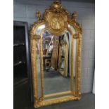 A very large giltwood and gesso wall mirror with relief decorated circular plaque and cherubs