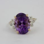 A 10ct yellow gold (stamped 10K) ring set with a large oval cut amethyst, L. 1.5cm, and diamond