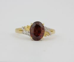 A hallmarked 9ct yellow gold ring set with an oval cut red tourmaline and diamonds, (O).