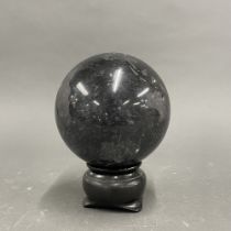 A polished black granite ball on a wooden stand, ball dia. 15cm.