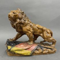 A large early 20th century hand painted pottery lion figure, H. 39cm, L. 50cm.