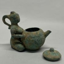 Antiquities interest. An archaic form bronze tea pot held by a kneeling female figure, spout to