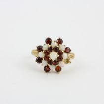 A hallmarked 9ct yellow gold cluster ring set with round cut garnets and opals, (O.5). One garnet