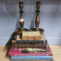A pair of turned oak candlesticks and a quantity of books.