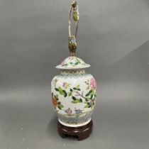 A Chinese hand painted porcelain jar and cover mounted as a lamp base on a wooden stand, H. 55cm.