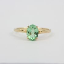 A hallmarked 9ct yellow gold (marked 10K) solitaire ring set with an oval cut peridot, (O).